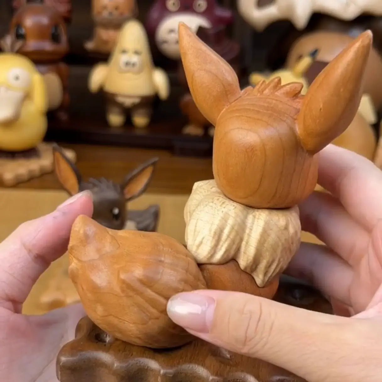 Back view of wooden Eevee figurine, highlighting carved tail and natural wood texture