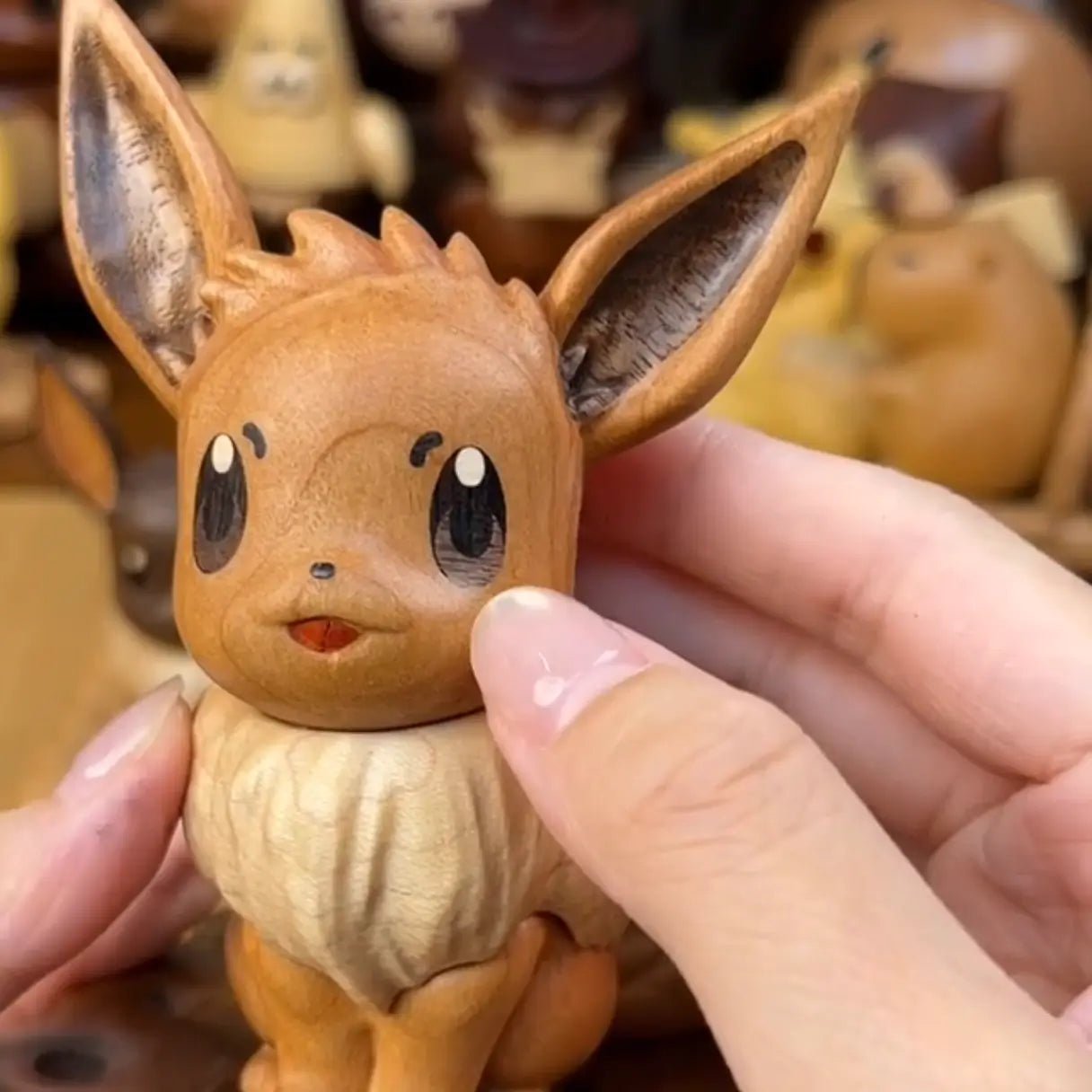 Close-up of wooden Eevee figurine head and face, showing fine hand-carved details and natural wood grain