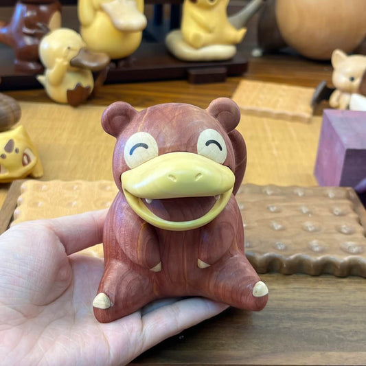 Hand holding a 7cm tall wooden Slowpoke figurine made of red cedar, boxwood, and white maple