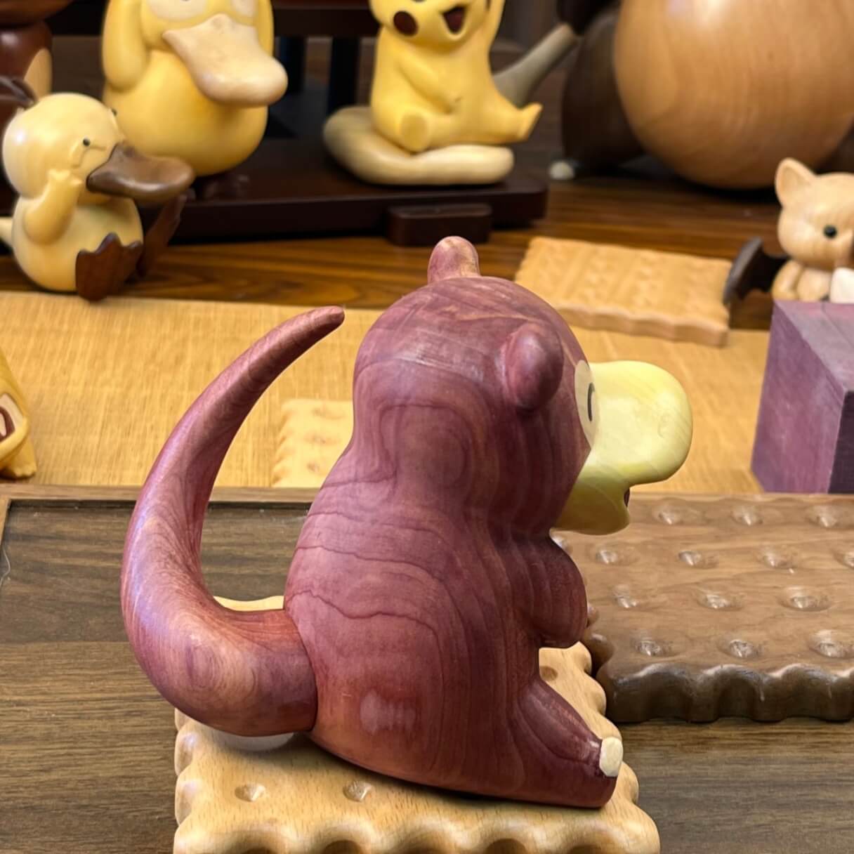 Back view of wooden Slowpoke figurine showing tail and natural wood grain details
