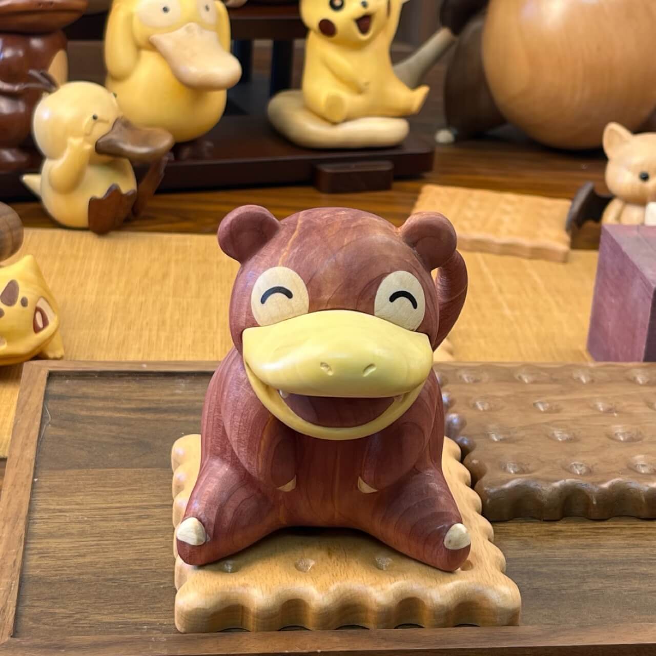 Front view of handcrafted wooden Slowpoke figurine made from red cedar and boxwood, sitting on a biscuit-shaped base