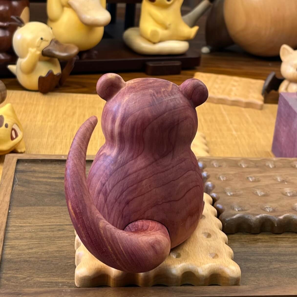 Side and rear angle of handcrafted wooden Slowpoke figurine, carved from red cedar with detailed wood texture